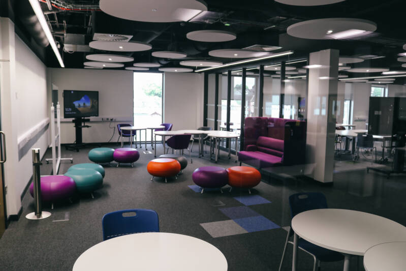 Modern open-plan learning resource centre, with tables, colourful seating and computer equipment.