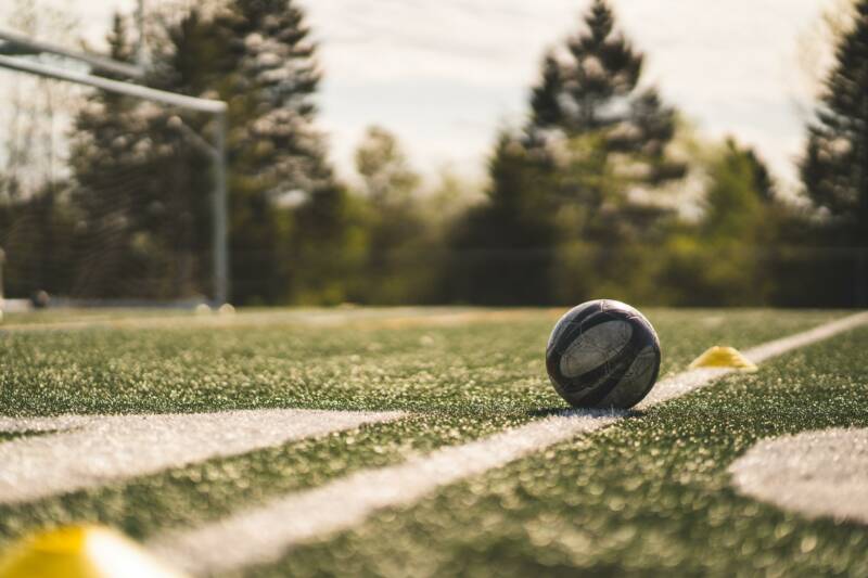 Close up of football on a football pitch with football net in the background
