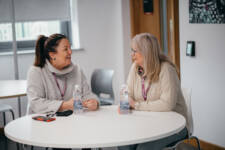Two SRC adult learners sitting at a table and smiling at each other