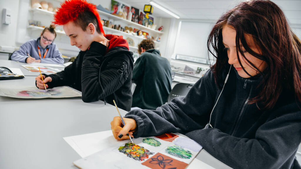 Art students sitting in an art studio. They are painting and drawing.