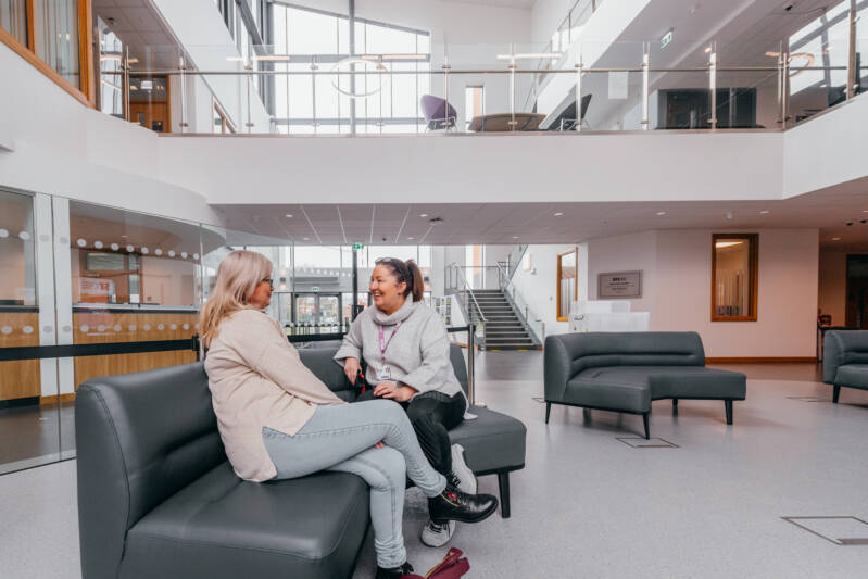 Two female SRC students sitting and chatting in a seating area within SRC campus