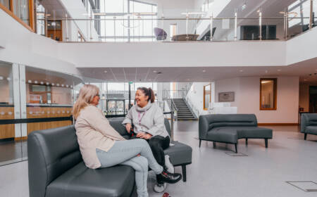 Two female SRC students sitting and chatting in a seating area within SRC campus