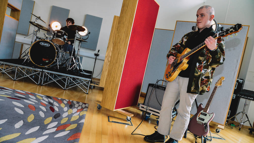 SRC student playing guitar within the music studio