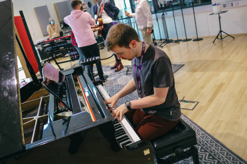 SRC student playing black piano in music studio