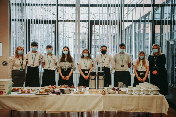 Group of people standing behind a table wearing face masks.