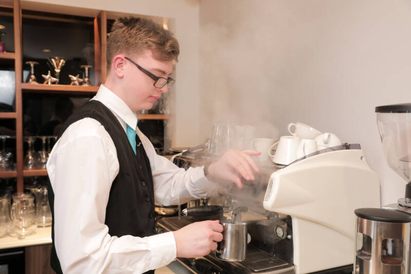 Cafe staff member using a coffee machine in SRC restaurant