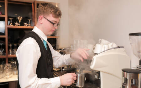 Cafe staff member using a coffee machine in SRC restaurant